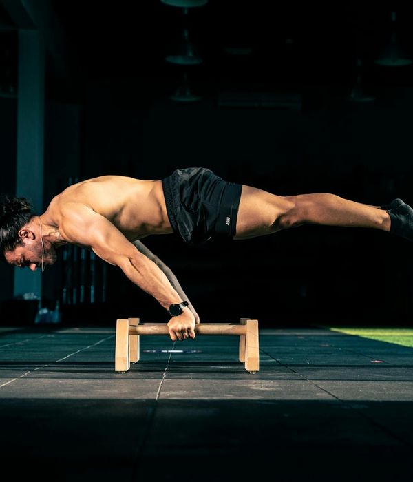 Man performing a controlled strength exercise in a dark, minimalist gym.